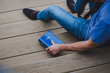 young man sitting on wooden steps next to a Bible 