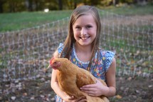 a little girl holding a chicken 