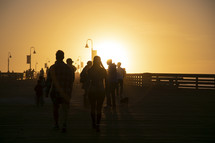 silhouettes of people on a pier at sunset 