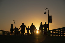 silhouettes of people on a pier at sunset 