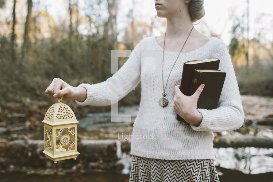 woman carrying a lantern and Bible and journal 