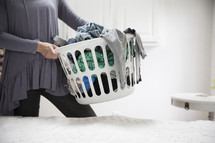 a woman holding a basket of dirty laundry.