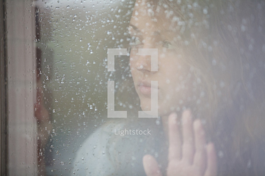 Girl looking out a frosted window pane.
