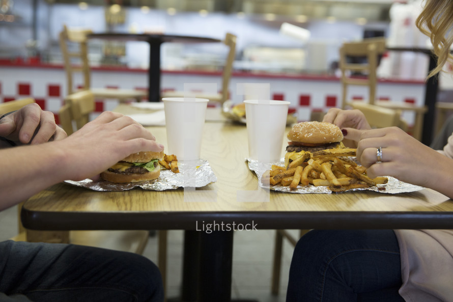 couple sitting across from one another eating fast food 
