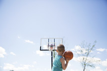 a boy playing basketball outdoors 