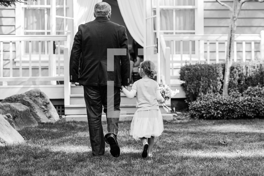 a father walking holding his daughter's hand 