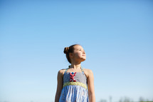 portrait of a girl standing against a blue sky 