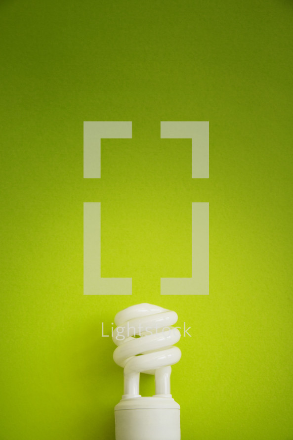 An energy efficient light bulb on a green background.