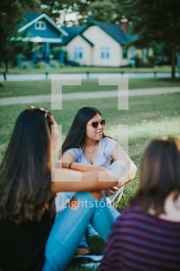 teen girls talking sitting in a circle in the grass