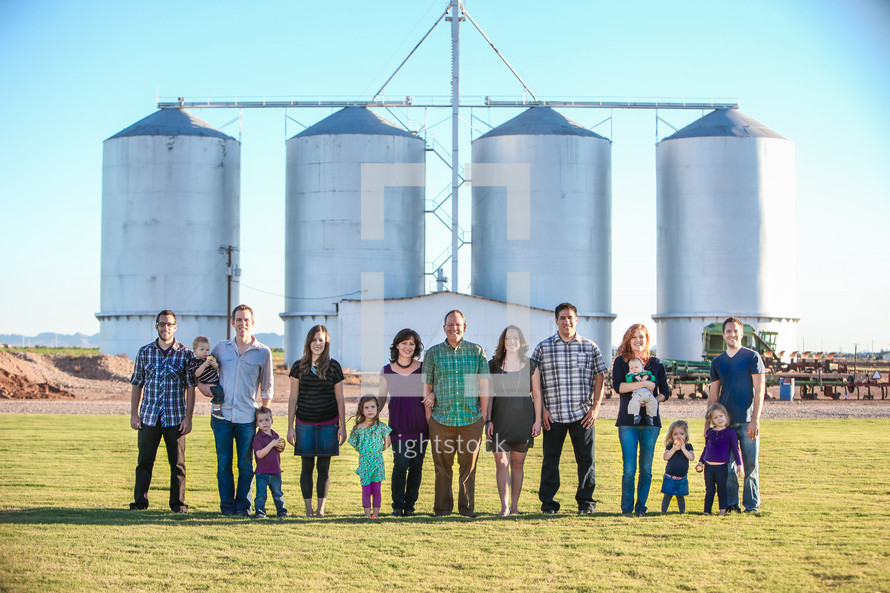 family standing on a farm in front of silos 
