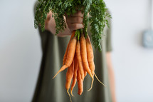 woman holding a bunch of carrots 