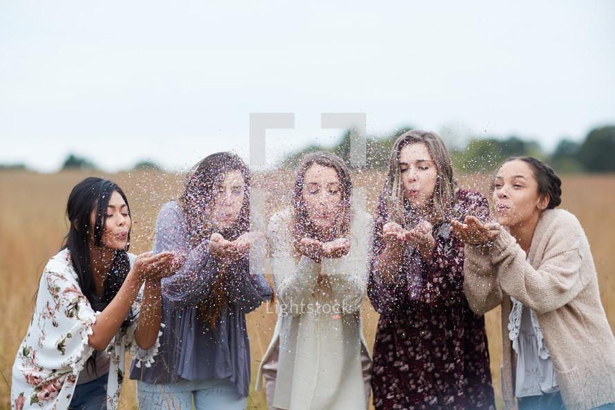 group of young women blowing confetti 