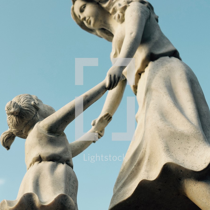 whimsical dancing mother and child statue against a blue sky 