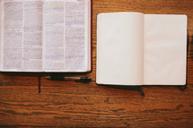 open Bible and open journal on a wood table 