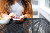 a woman sitting at an outdoor table and texting 