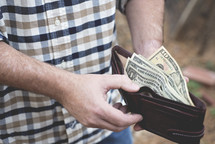 a man holding a wallet full of cash 