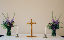 cross, candle, and flowers on an altar 