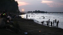 people sitting on a beach at night waiting for fireworks 