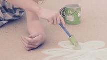 a little girl painting a shamrock with sidewalk chalk paint 