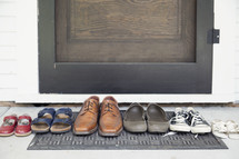 row of a families shoes on a door mat 