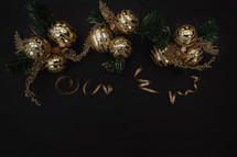 gold Christmas ball ornaments and ribbon on a black background 