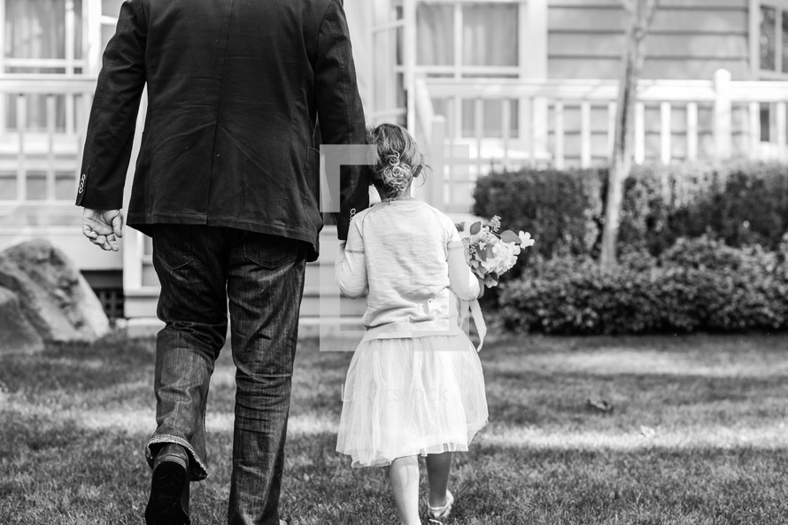 a father walking holding hands with his daughter 