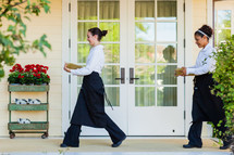 caterers  servers carrying plates across porch. 
