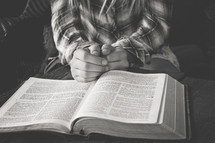 a teen girl praying near an open Bible 