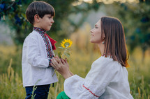 Tender scene of loving son with mom on apple garden backdrop with sunlight. Beautiful family. Cute 4 years old kid with mother. Parenthood, childhood, happiness, children wellbeing concept.
