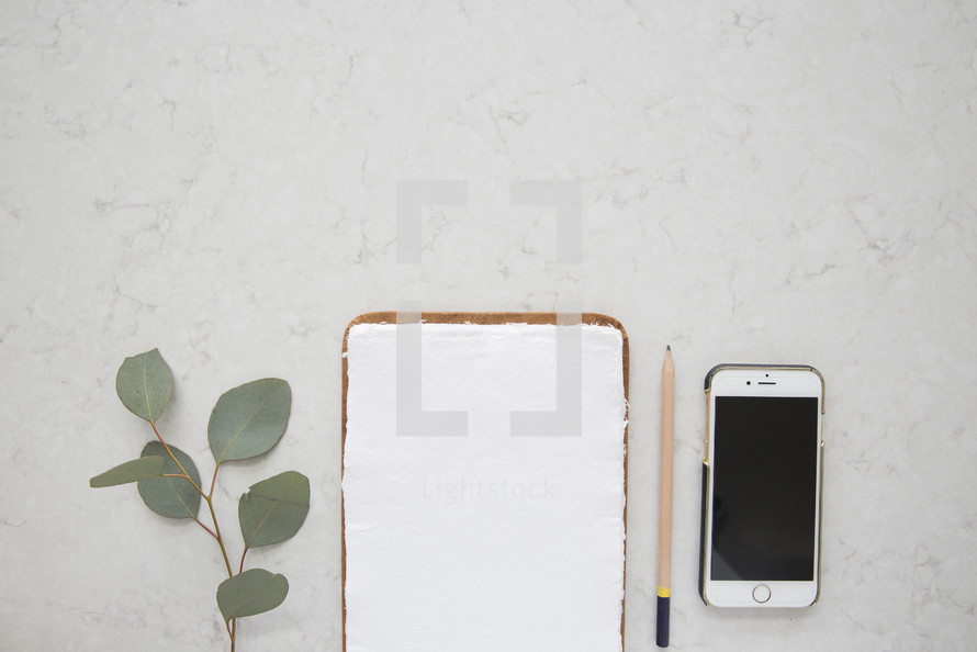 iPhone, notepad, paper, pencil, and eucalyptus leaves, on a white background 
