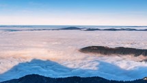 Time lapse of foggy mountains with low clouds flowing throughout. 
