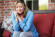 a woman praying while sitting on a porch 
