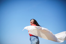 a woman with outstretched arms holding a white sheet 