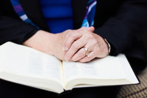 elderly woman with praying hands over a Bible 