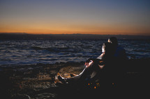 couple snuggling on a beach at night in front of a fire 
