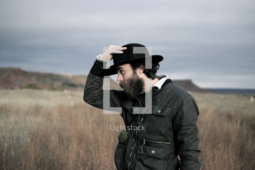 man with a black hat outdoors in a field 