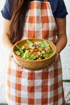 a woman holding a bowl of salad 