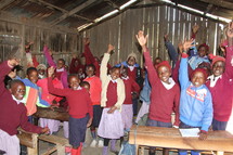 kids with hands raised in a schoolhouse 