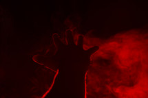 glowing hand over red smoke. 