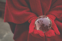 gloved hands holding a glass globe 