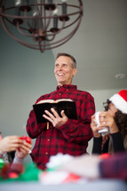 A man reading the Bible to a group at a Christmas party