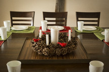 set table, centerpiece, candles, pine cone, wreath, table, place settings 