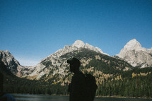 silhouette of a man near a mountain lake 