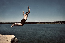 Man jumping off rock into the lake