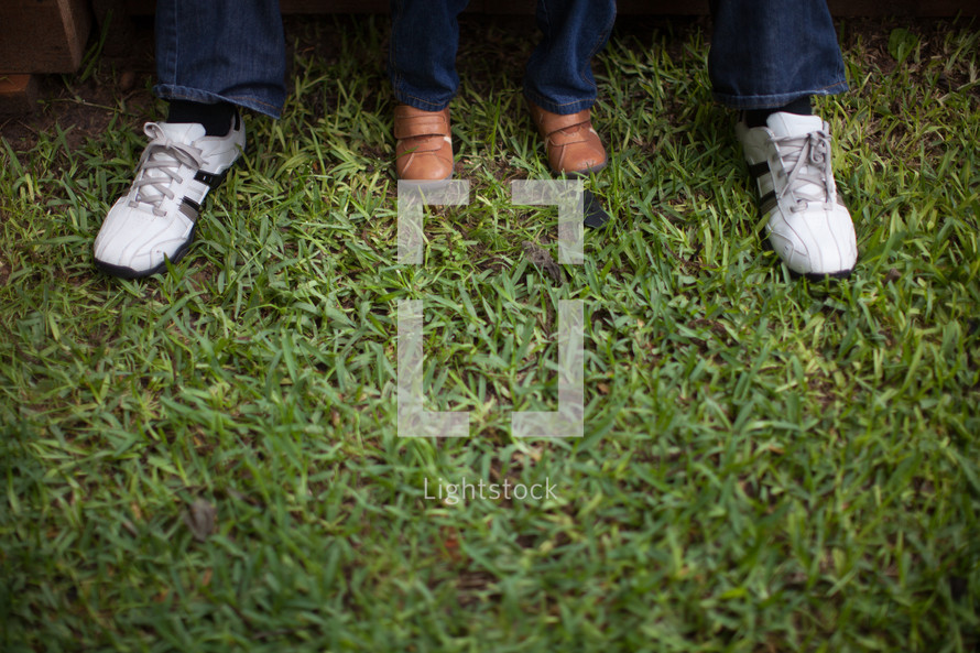 feet of a father and son in grass