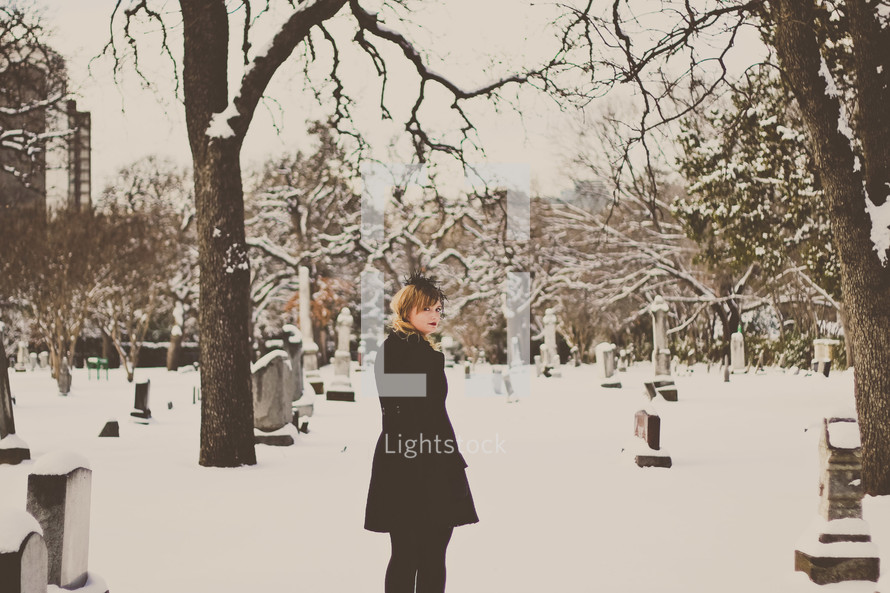 grieving woman in black standing in a cemetery 