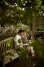 A Married couple reading the Bible in a park.