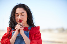 portrait of a woman standing outdoors with praying hands 