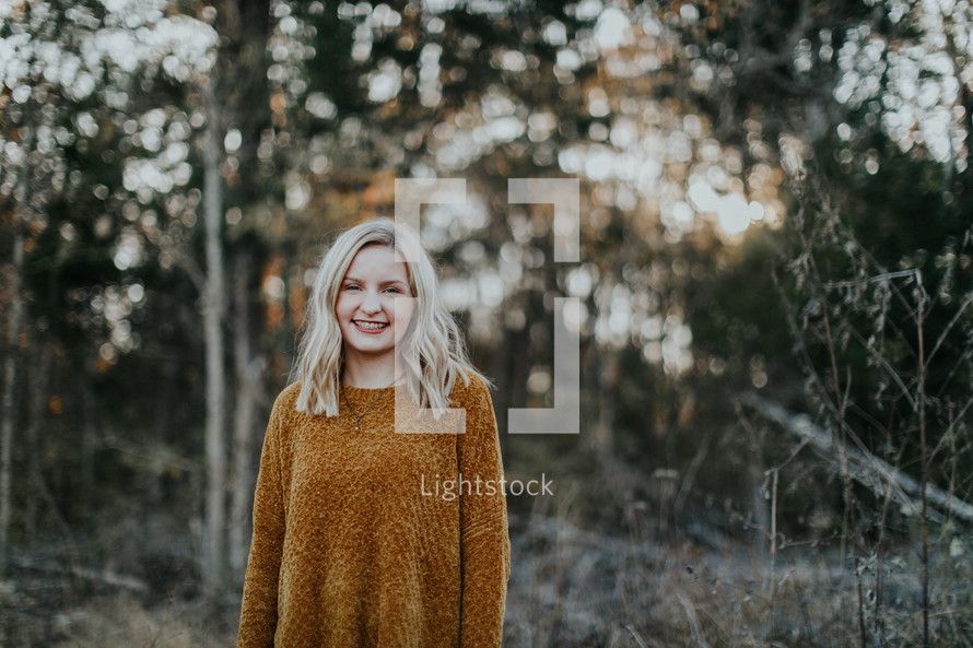 smiling woman standing outdoors in a sweater 