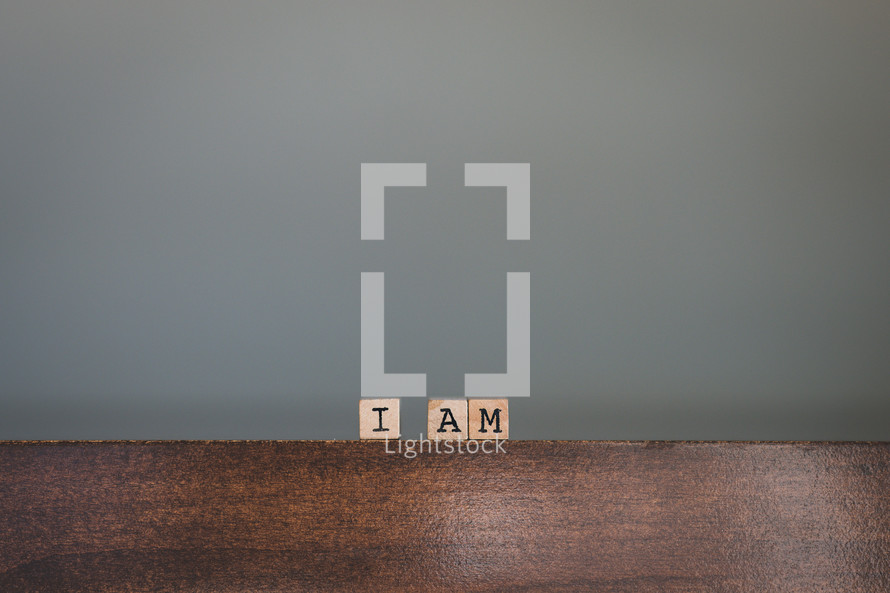 Wooden tiles spelling "I Am" on wooden table